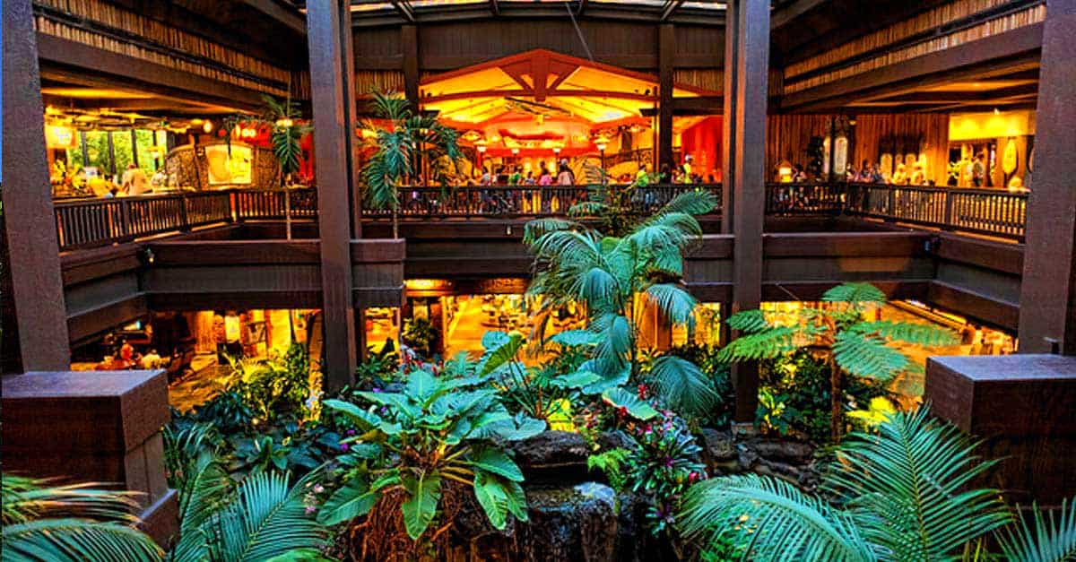 Vibrant indoor jungle with lush greenery, wooden walkways, and guests enjoying festive dining in a lively themed restaurant.