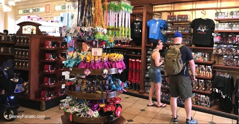 Guests exploring shelves filled with Disney toys, apparel, and souvenirs in a vibrant Disney Parks merchandise shop.