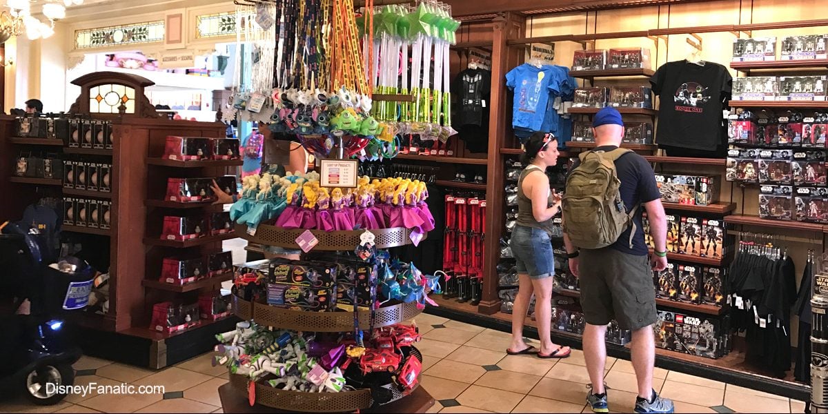 Guests exploring shelves filled with Disney toys, apparel, and souvenirs in a vibrant Disney Parks merchandise shop.