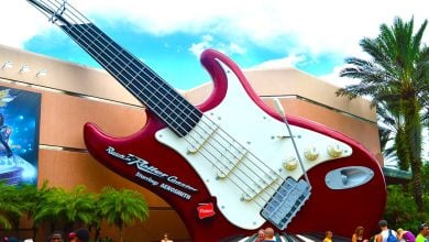 The iconic red guitar greets guests outside Rock 'n' Roller Coaster at Hollywood Studios, surrounded by palm trees and visitors.