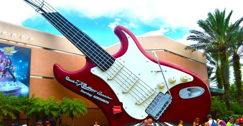 The iconic red guitar greets guests outside Rock 'n' Roller Coaster at Hollywood Studios, surrounded by palm trees and visitors.