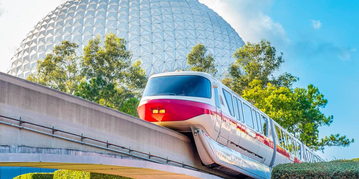 The Walt Disney World monorail glides past Epcot’s iconic Spaceship Earth under a bright Florida sky, framed by lush greenery.