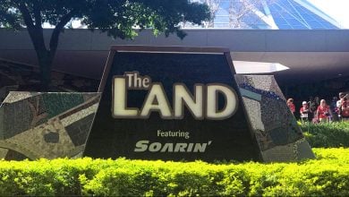 The Land Pavilion entrance sign with Soarin’ highlighted at Epcot, surrounded by lush landscaping and visiting guests.