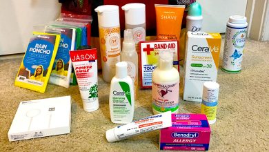 Various health and hygiene products—including sunscreen, allergy medicine, lotions, rain ponchos, and more—are neatly arranged on a beige carpeted floor, ready for Disney World vacation planning.