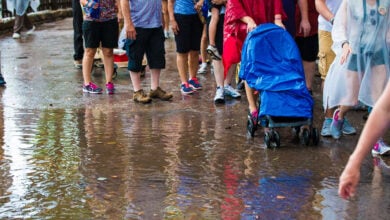 Guests wade through a puddle at Disneyland, their stroller protected by a blue rain cover—proof that smart packing keeps families dry.