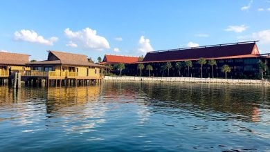 Tropical-inspired Disney resort by the water, palm trees, and blue skies mirrored in the lagoon—perfect for vacation magic.