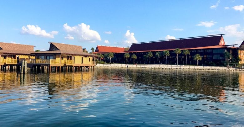 Tropical-inspired Disney resort by the water, palm trees, and blue skies mirrored in the lagoon—perfect for vacation magic.