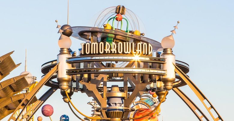 Tomorrowland entrance sign gleams with metallic flair and orbiting planets, inviting guests into the futuristic Disney adventure.