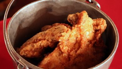 Crispy fried chicken served in a themed metal bucket atop a carnival-red table, perfect for refueling at an amusement park eatery.