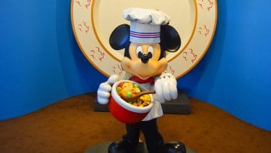 Chef Mickey Mouse delights guests, holding a vibrant cereal bowl and spoon, ready for breakfast magic at Disney World.