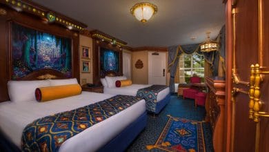 Fairytale-themed Disney resort room with two queen beds, vibrant bedding, and storybook artwork above each bed.