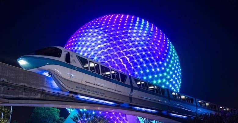 A futuristic monorail glides in front of the illuminated geodesic sphere of Epcot at night, glowing with vibrant blue and purple lights—a spectacular example of how to get around Disney World in style.