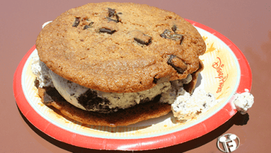 A gooey chocolate chip cookie ice cream sandwich on a Disney Parks plate—Disney fans’ go-to treat to beat the summer heat.