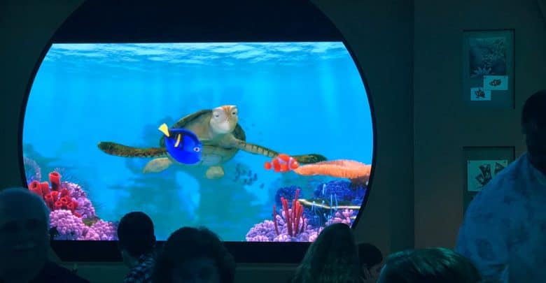 Crush and friends from Finding Nemo swim across the massive Turtle Talk with Crush screen as guests watch in the audience.