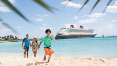 A cheerful kid races along a beach with relatives as a cruise ship, ready for onboard adventures, gleams on the turquoise sea.