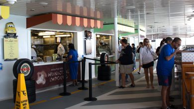 Guests at a Cars-themed quick-service counter aboard Disney Cruise Line, greeted by a chef and menu inspired by Radiator Springs.