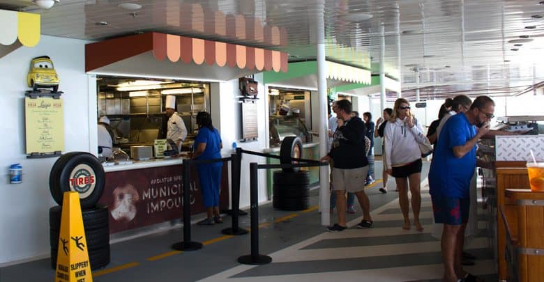 Guests at a Cars-themed quick-service counter aboard Disney Cruise Line, greeted by a chef and menu inspired by Radiator Springs.