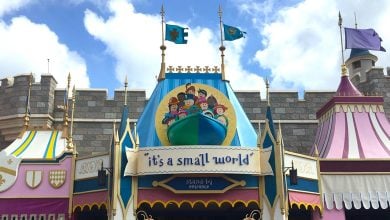 The whimsical entrance to "it's a small world" in Fantasyland, with vibrant decor and festive flags beneath a partly cloudy sky.