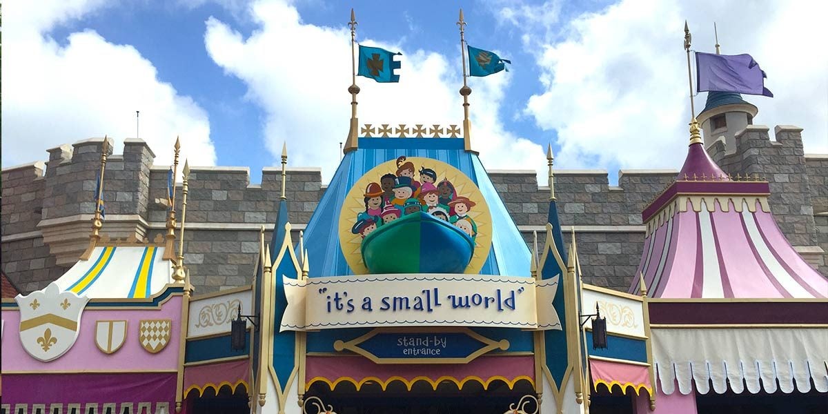 The whimsical entrance to "it's a small world" in Fantasyland, with vibrant decor and festive flags beneath a partly cloudy sky.