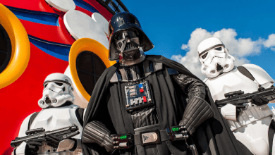 Darth Vader and Stormtroopers strike a pose before a vibrant Disney Cruise ship featuring iconic Mickey Mouse artwork.