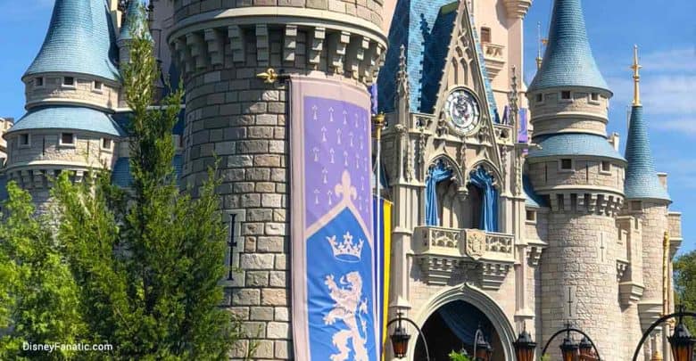 Iconic Cinderella Castle at Walt Disney World, featuring blue turrets and a lavender banner against the vibrant park atmosphere.