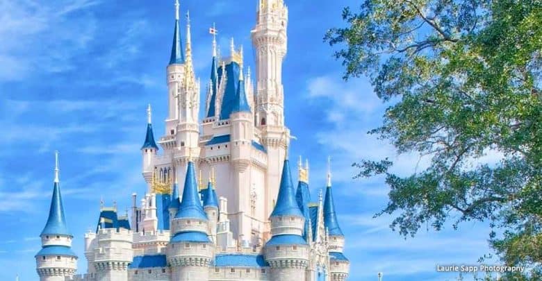 Sleeping Beauty Castle’s blue and white spires shine against a sunny sky, with lush greenery framing the iconic Disney park view.