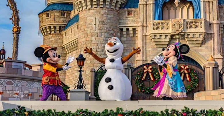 Mickey, Olaf, and Minnie light up the Disney castle stage in holiday attire during a magical theme park celebration.