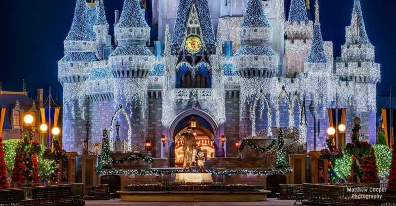 Cinderella Castle at Magic Kingdom sparkling with white holiday lights and festive Christmas décor during nighttime festivities.
