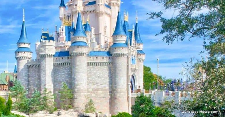 The iconic Cinderella Castle with sparkling blue spires, nestled in lush gardens under a sunny Disney World sky.
