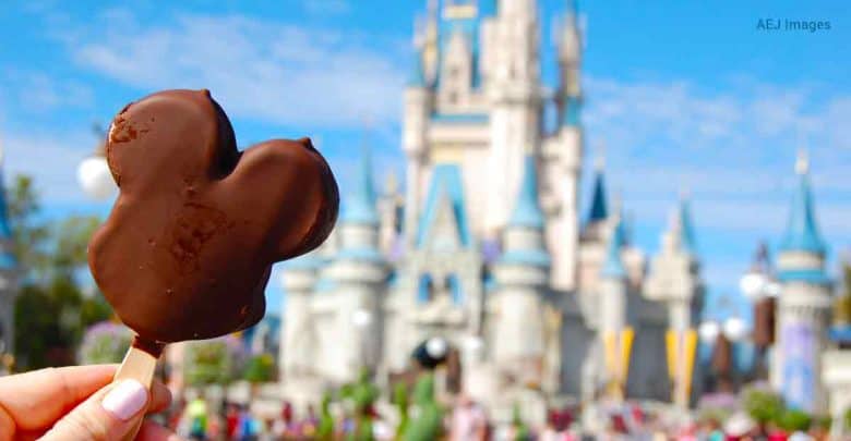 Savoring a classic Mickey Mouse ice cream bar with Cinderella Castle in the background on a bright Disney World day.
