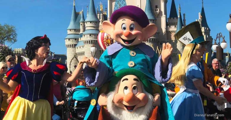Snow White, Dopey, and Alice greet guests in front of the iconic castle at Disneyland, ready for photos and magical memories.