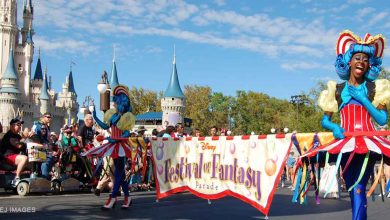 Festival of Fantasy Parade performers lead with the signature banner at Magic Kingdom, signaling a can't-miss Disney celebration.