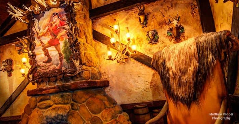 Inside a theme park’s immersive tavern, antlers, barrels, and a grand hunter painting decorate stone walls for guests.