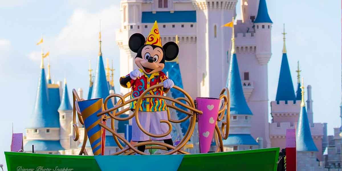 Mickey Mouse waves to fans from a vibrant parade float in front of Cinderella Castle at Disney World.