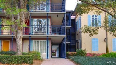 Colorful apartment-style accommodations with blue railings and pastel doors, nestled amid lush landscaping near the park.