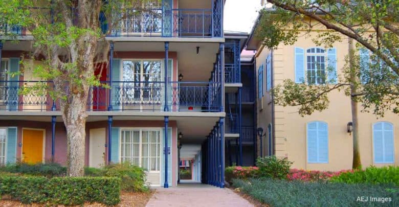 Colorful apartment-style accommodations with blue railings and pastel doors, nestled amid lush landscaping near the park.
