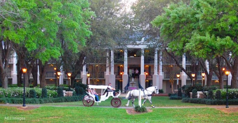 White horse-drawn carriage awaits on manicured lawn before a grand columned building, evoking Disney World fairytale magic.