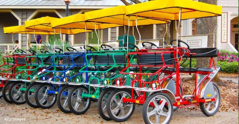 Brightly colored surrey bikes with yellow canopies await guests outside the park’s main entrance, ready for family fun.