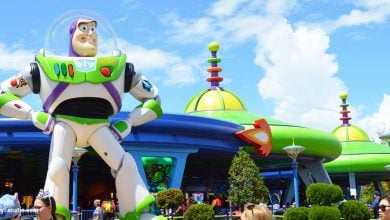 Buzz Lightyear greets guests outside Toy Story Land’s vibrant, space-themed attraction on a bright, sunny day.