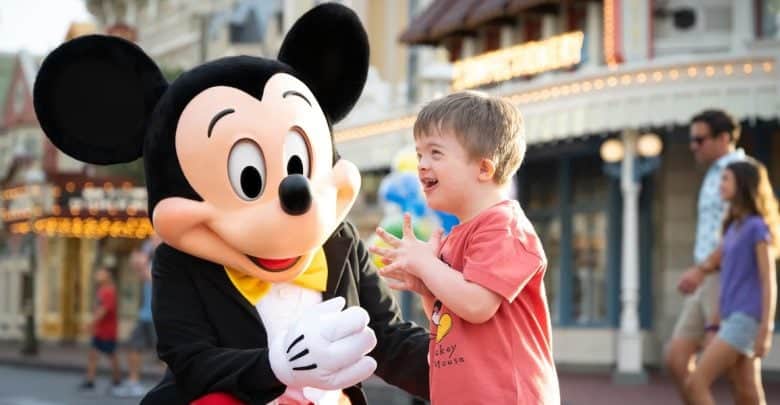 A child smiling excitedly while meeting a person in a Mickey Mouse costume at a theme park, capturing the magic of Disney World changes amid colorful buildings and cheerful crowds in the background.