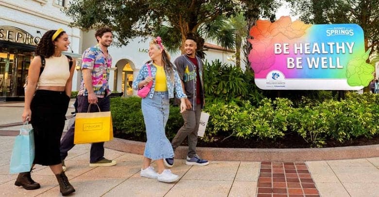 Four young adults walk and smile together in Disney Springs