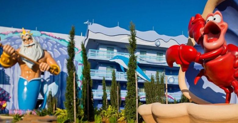 King Triton and Sebastian statues welcome guests outside Disney’s Art of Animation Resort, set against a brilliant blue sky.