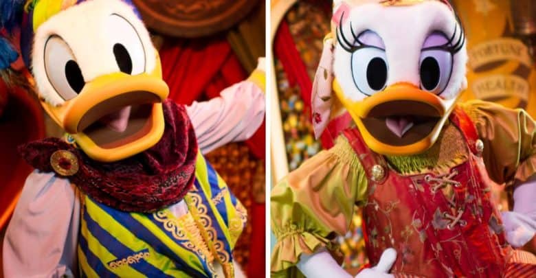 Two animated characters resembling a duck couple, dressed in colorful, elaborate costumes reminiscent of Minnie Mouse's signature style. The left character wears a blue and yellow striped outfit with a purple scarf, while the right character sports a red and green dress with a patterned headscarf.