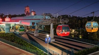 A Disney Skyliner gondola station at night, with colorful cabins gliding along cables. The area is well-lit, and the Twilight Zone Tower of Terror looms in the background—perfect for guests seeking Disney park exit tips after a magical day.