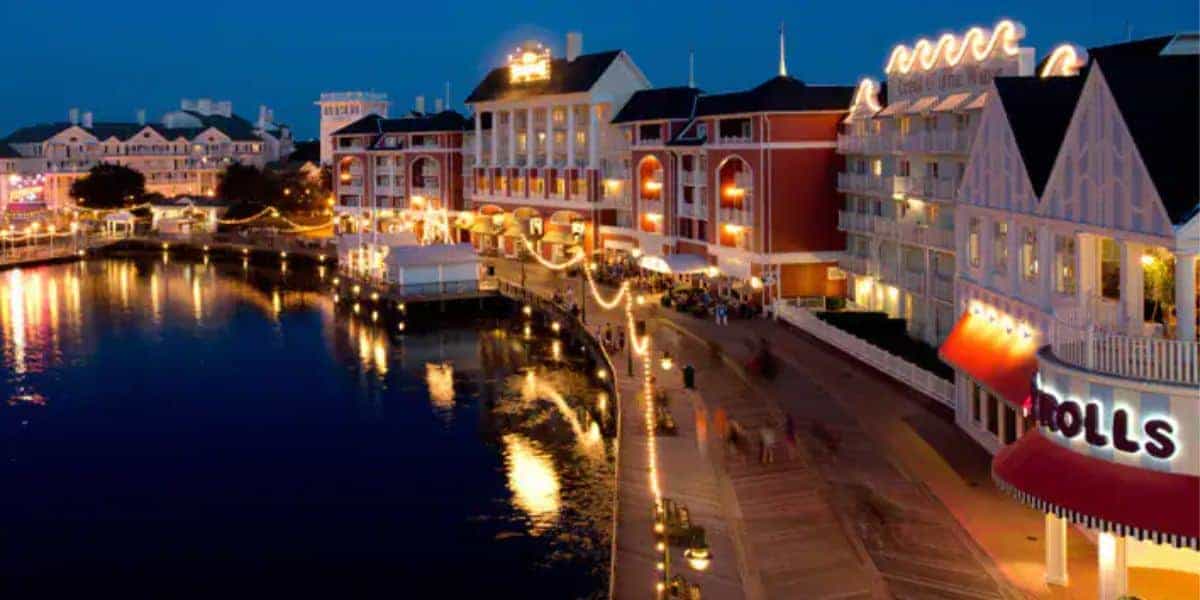 Disney’s BoardWalk sparkles at night, with vibrant shops and eateries aglow, inviting guests to enjoy lakeside entertainment.