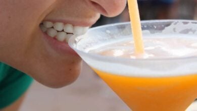 A person taking a sip of a drink while Drinking Around the World at EPCOT.
