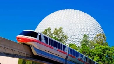 The Walt Disney World monorail glides past Epcot’s iconic Spaceship Earth, set against a flawless blue Florida sky.