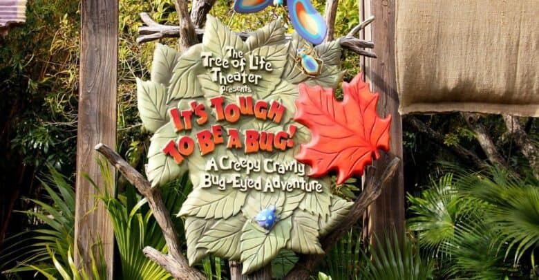 A colorful sign shaped like leaves and branches reads, "The Tree of Life Theater presents It's Tough to Be a Bug! A Creepy Crawly Bug-Eyed Adventure," with bug and leaf decorations around it.