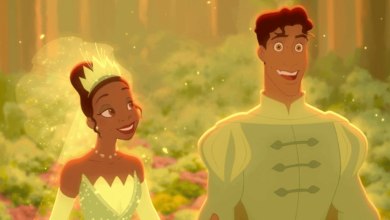 Princess Tiana in her green gown and Prince Naveen greet guests with smiles in an enchanting, illuminated forest at Disneyland.