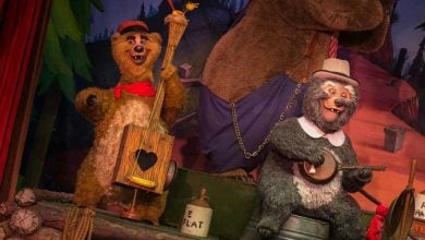 The Country Bears perform lively music on their vibrant stage, surrounded by whimsical forest-themed scenery.
